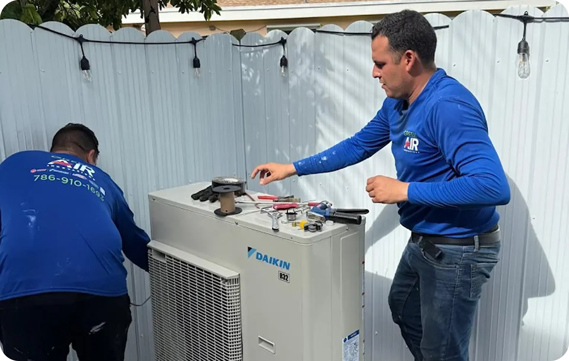 Technicians servicing an outdoor AC unit